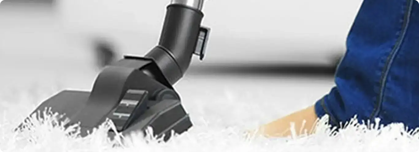 Close-up of a professional vacuuming a white carpet in Hampstead.